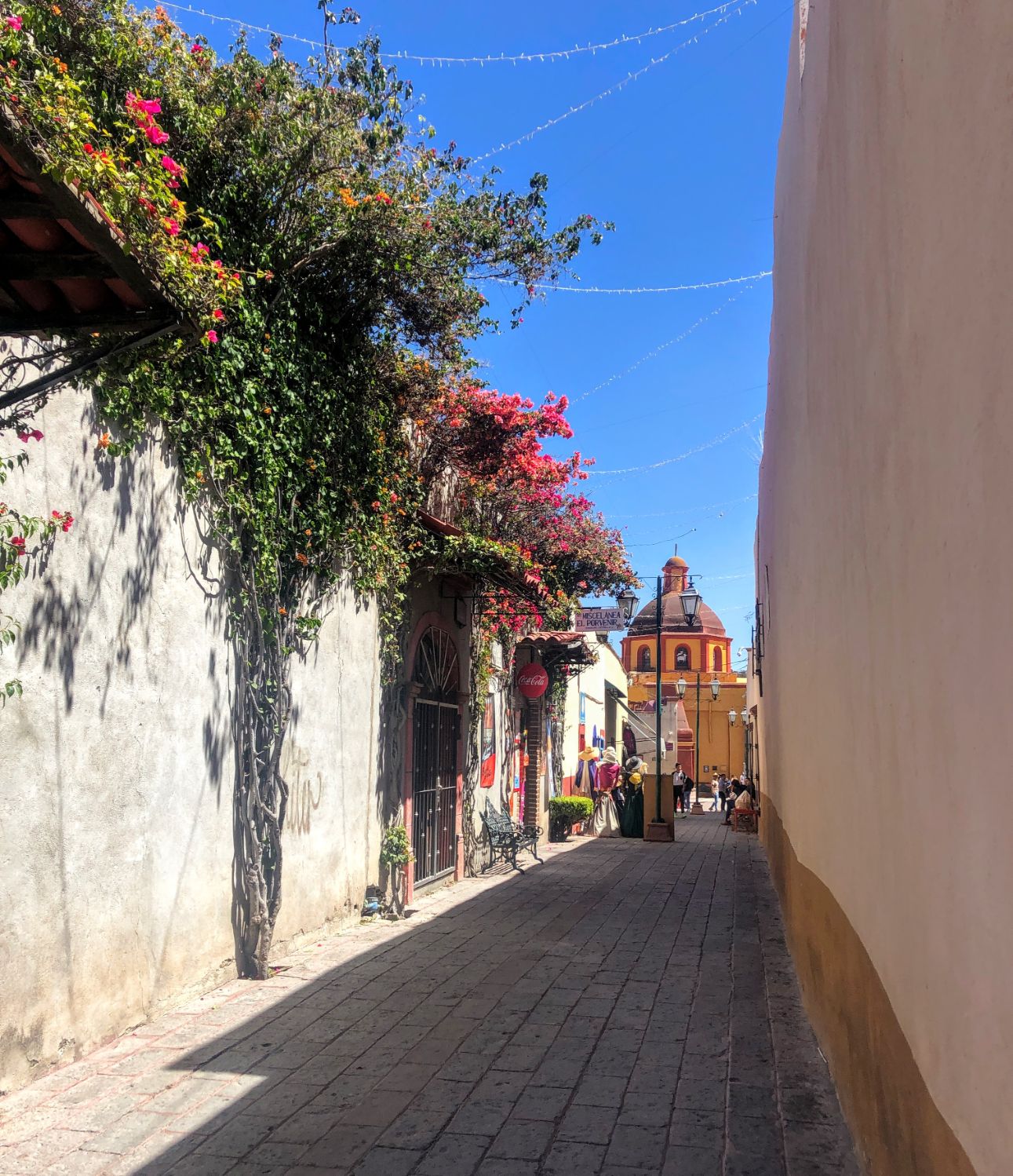 center of Bernal with a street covered in flowers and an orange church